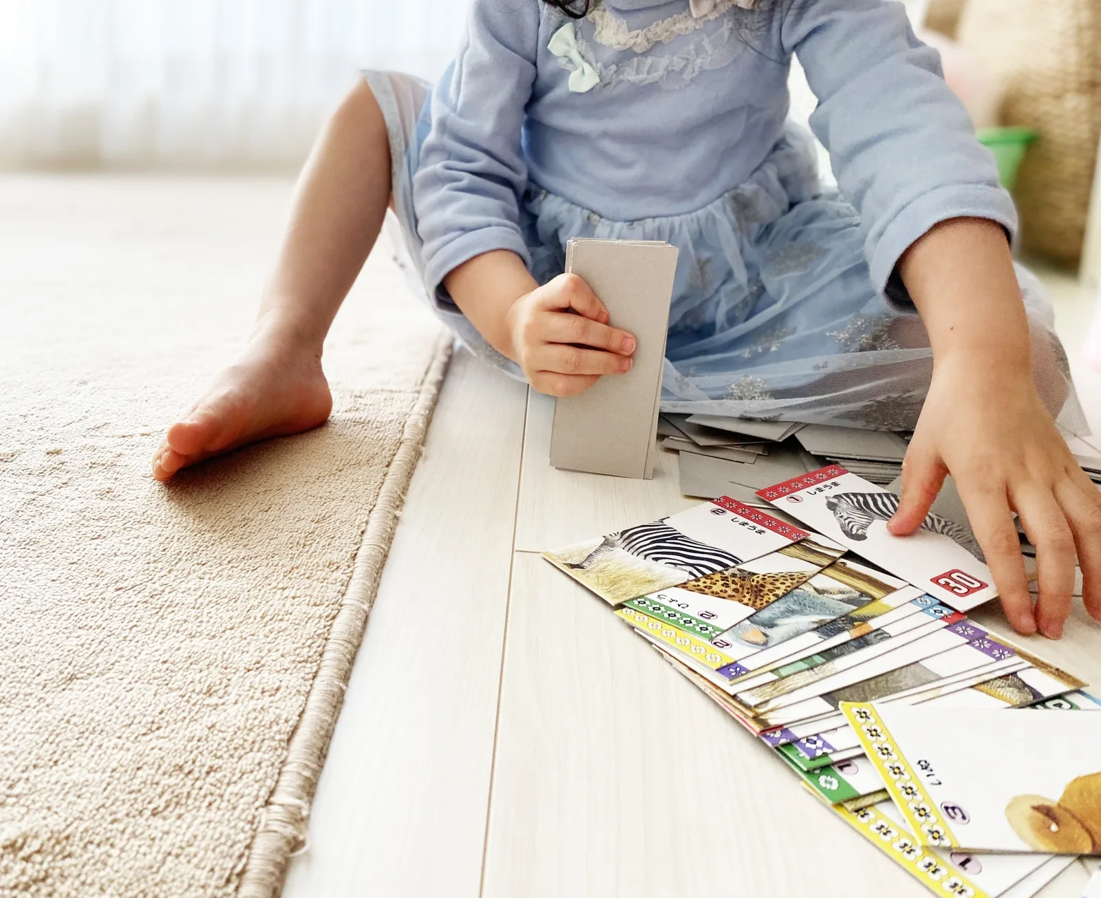 床に座ってカードで遊んでいるお子様